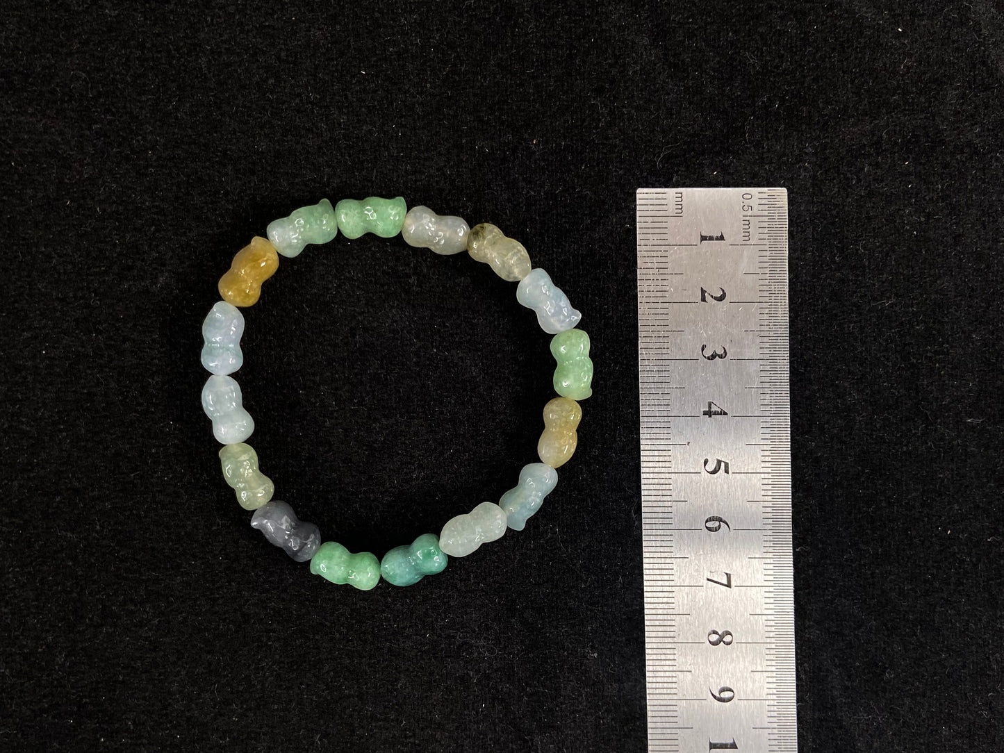 A strand of peanut shaped jade beads in soft yellow, green, brown, grey and ombre white to deep green.