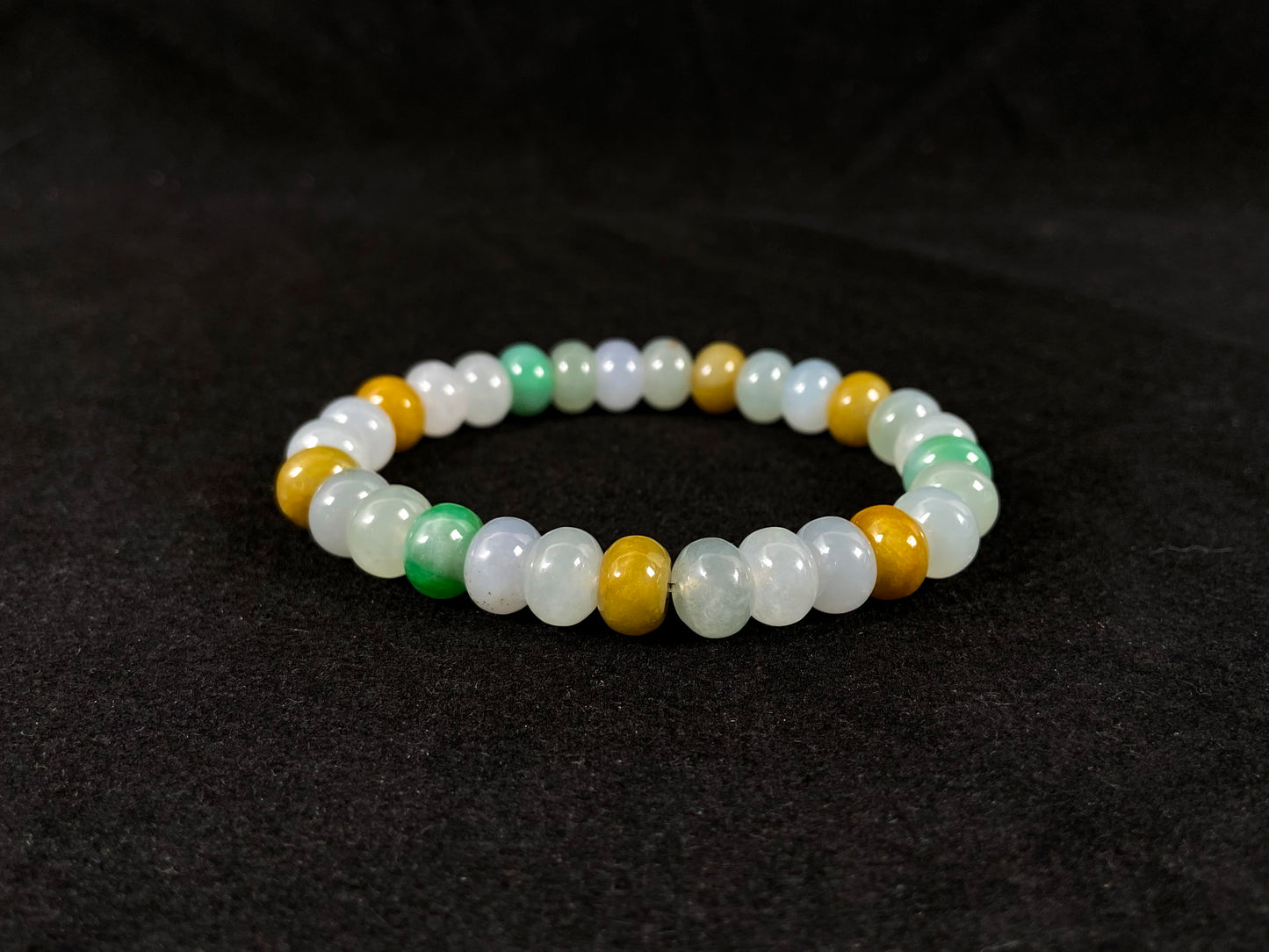 A jade bead strand featuring green, brown, yellow, white, and icy toned beads.