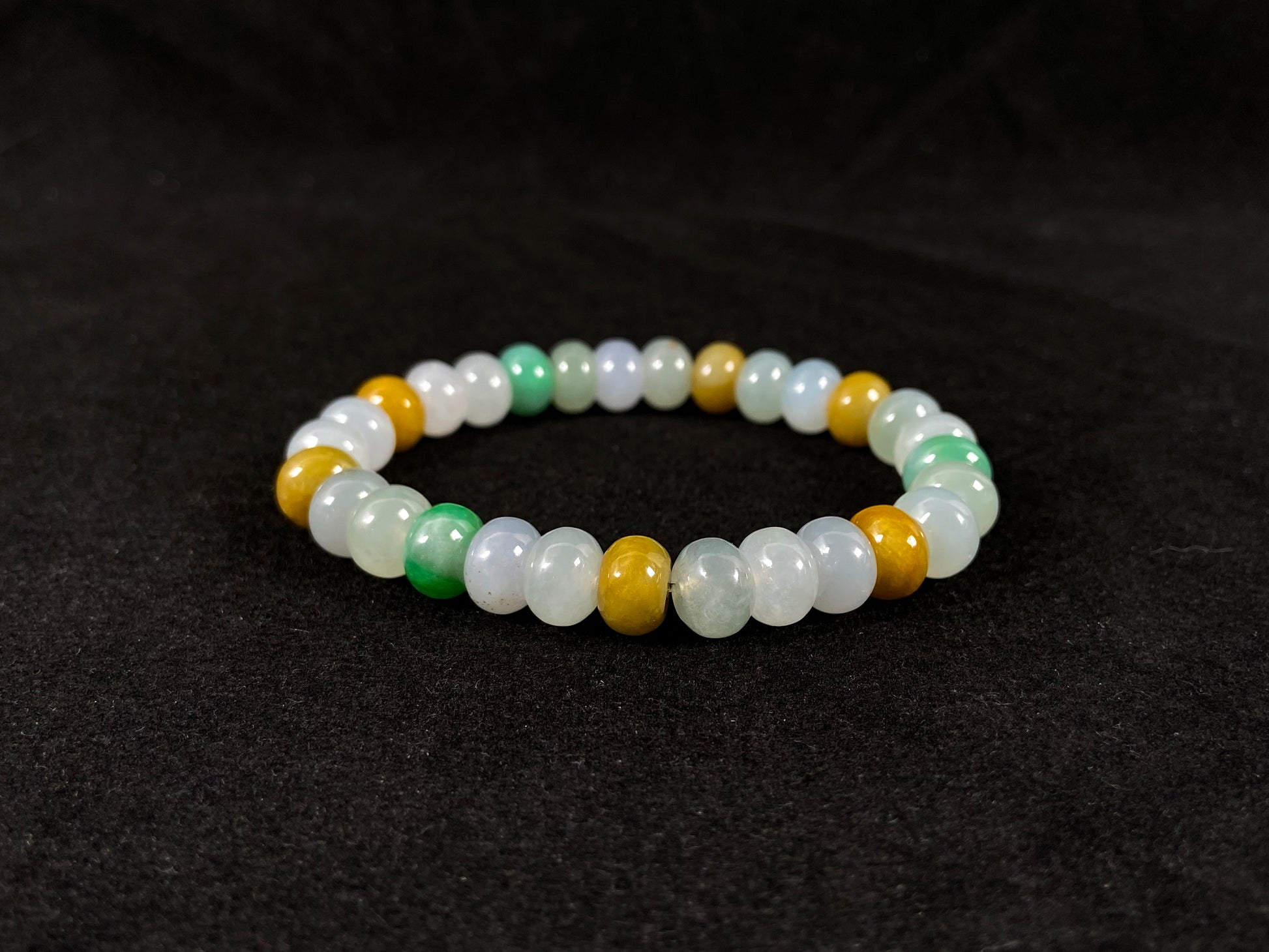 A jade bead strand featuring green, brown, yellow, white, and icy toned beads.