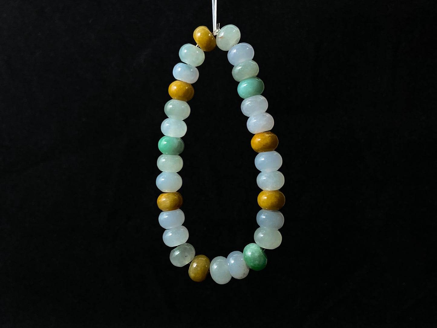 A jade bead strand featuring green, brown, yellow, white, and icy toned beads.