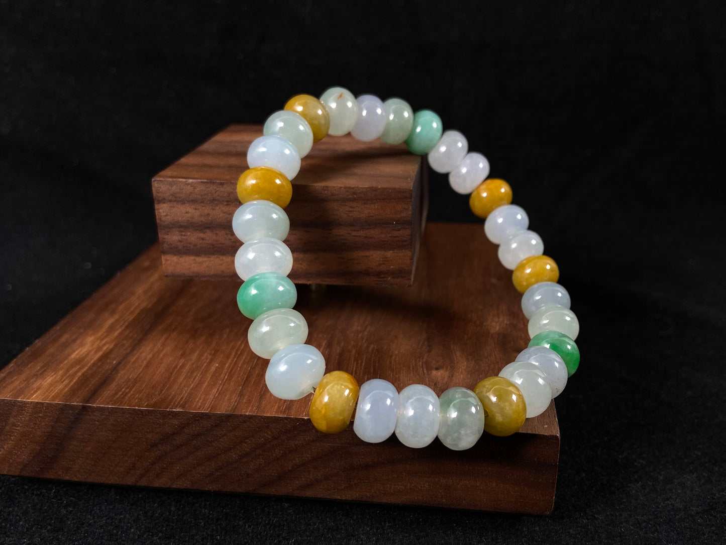 A jade bead strand featuring green, brown, yellow, white, and icy toned beads.