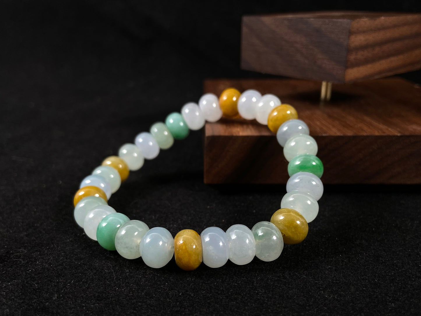 A jade bead strand featuring green, brown, yellow, white, and icy toned beads.