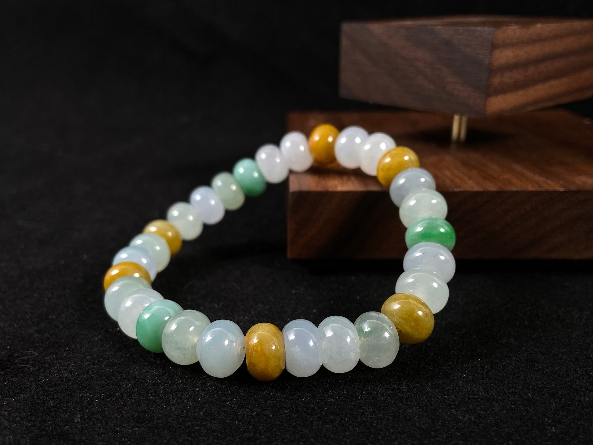 A jade bead strand featuring green, brown, yellow, white, and icy toned beads.