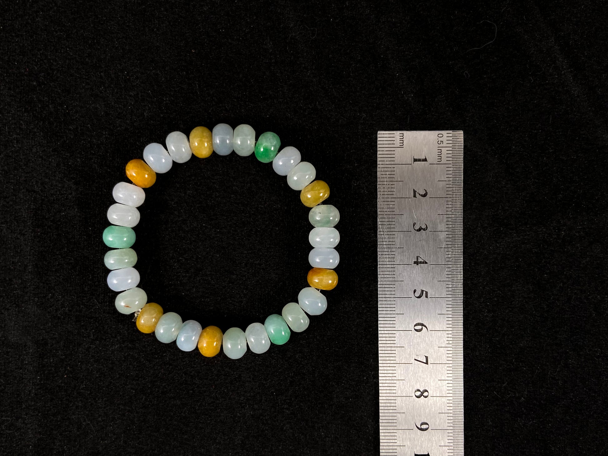 A jade bead strand featuring green, brown, yellow, white, and icy toned beads.