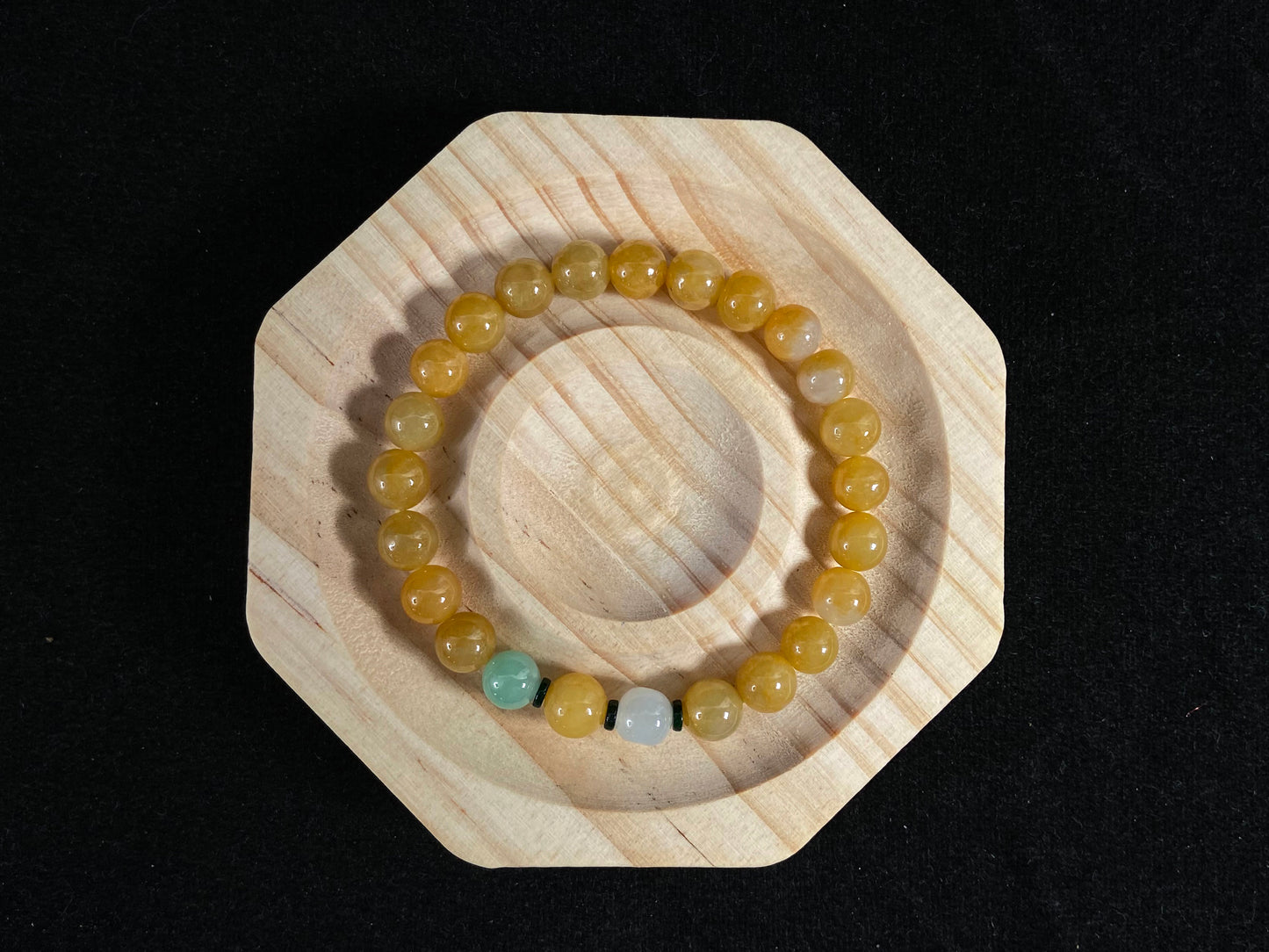This jade bracelet has mostly yellow beads, plus one apple green and one creamy white bead.