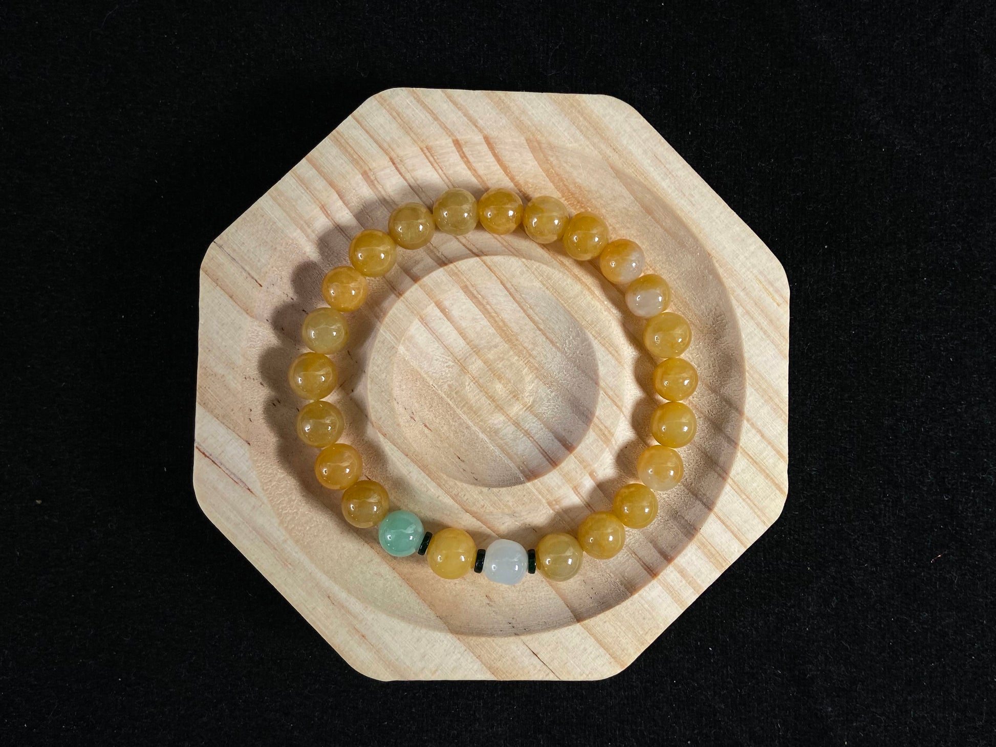 This jade bracelet has mostly yellow beads, plus one apple green and one creamy white bead.
