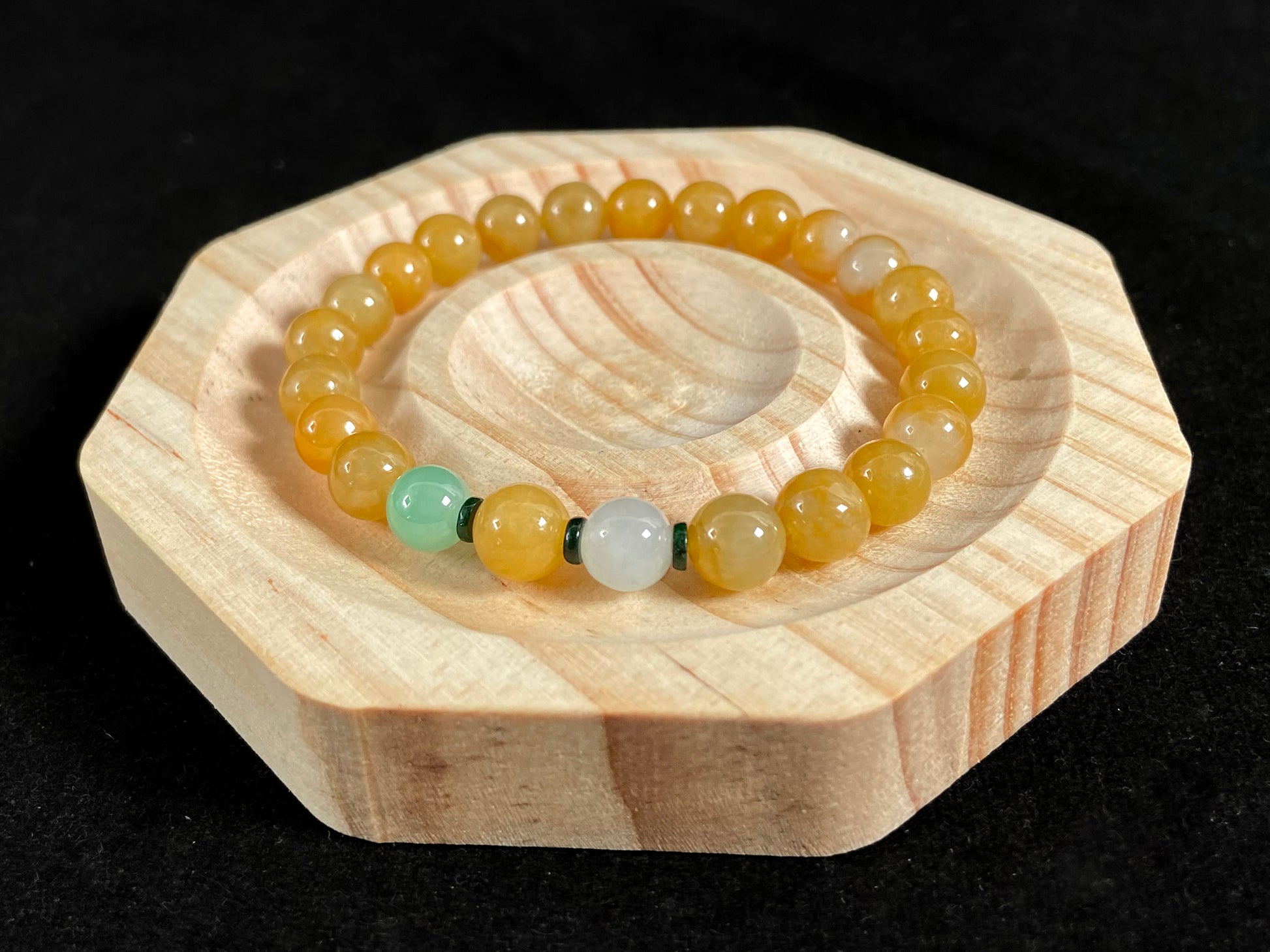 This jade bracelet has mostly yellow beads, plus one apple green and one creamy white bead.