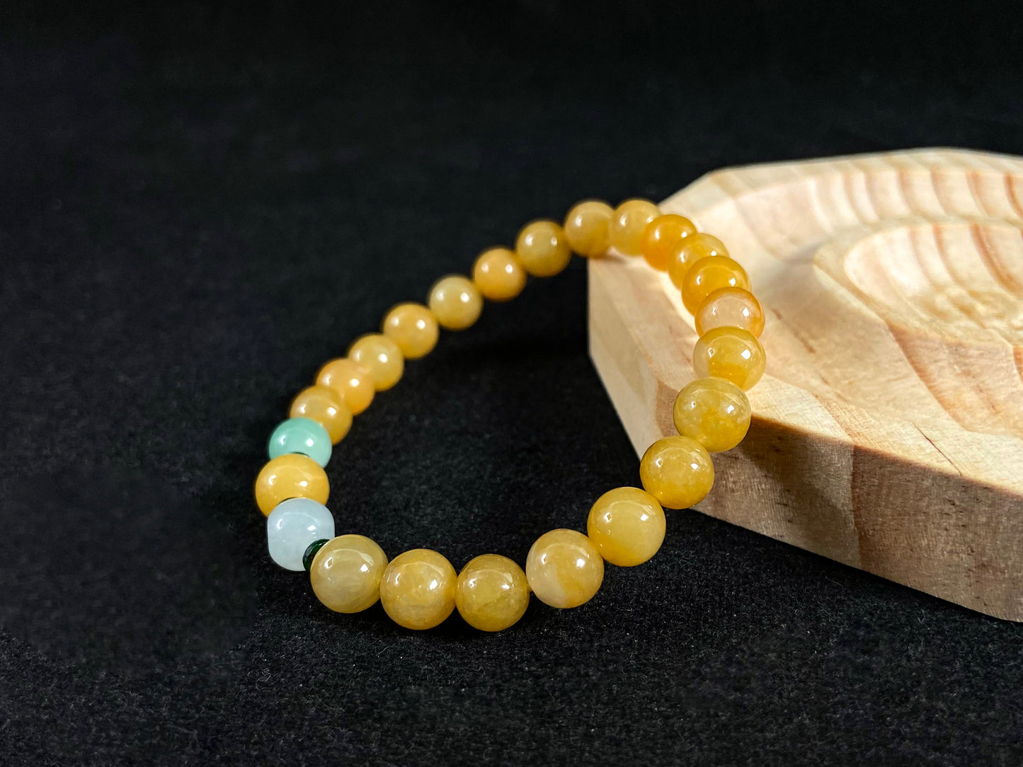 This jade bracelet has mostly yellow beads, plus one apple green and one creamy white bead.