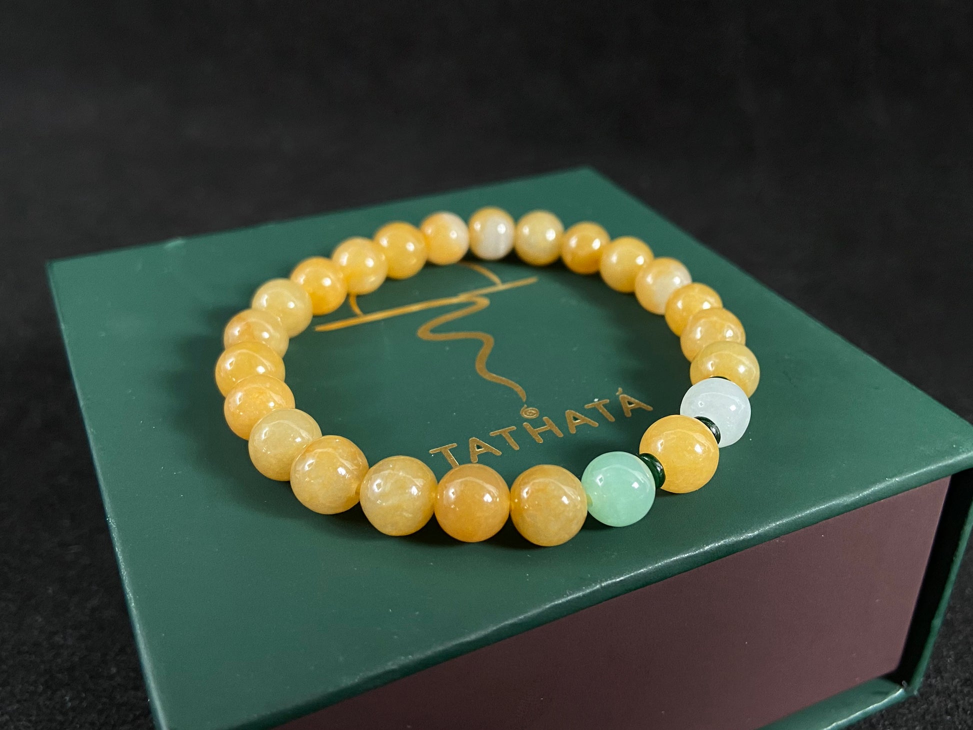 This jade bracelet has mostly yellow beads, plus one apple green and one creamy white bead.