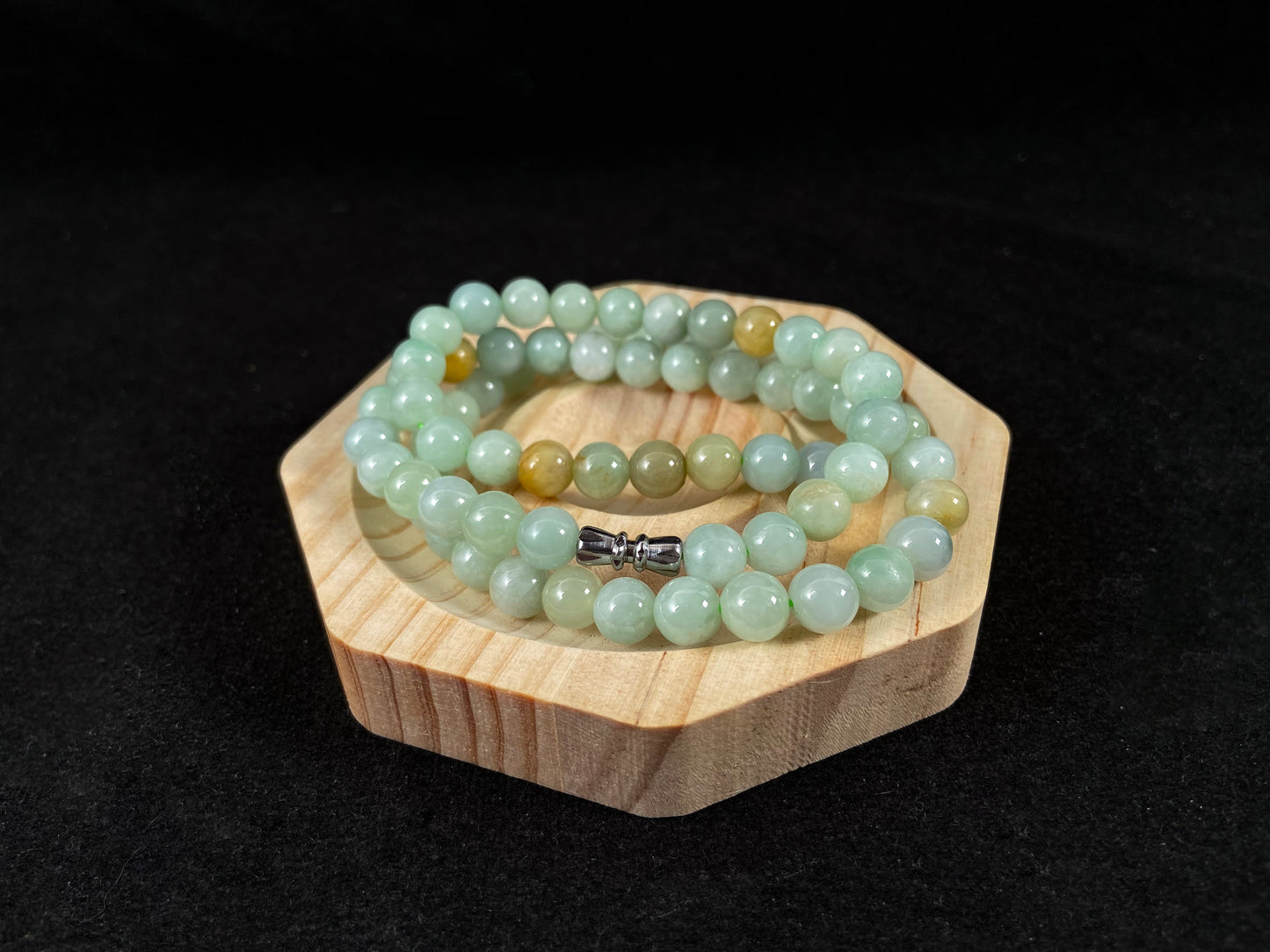 A light green jade bead strand with subtle tan brown accents.