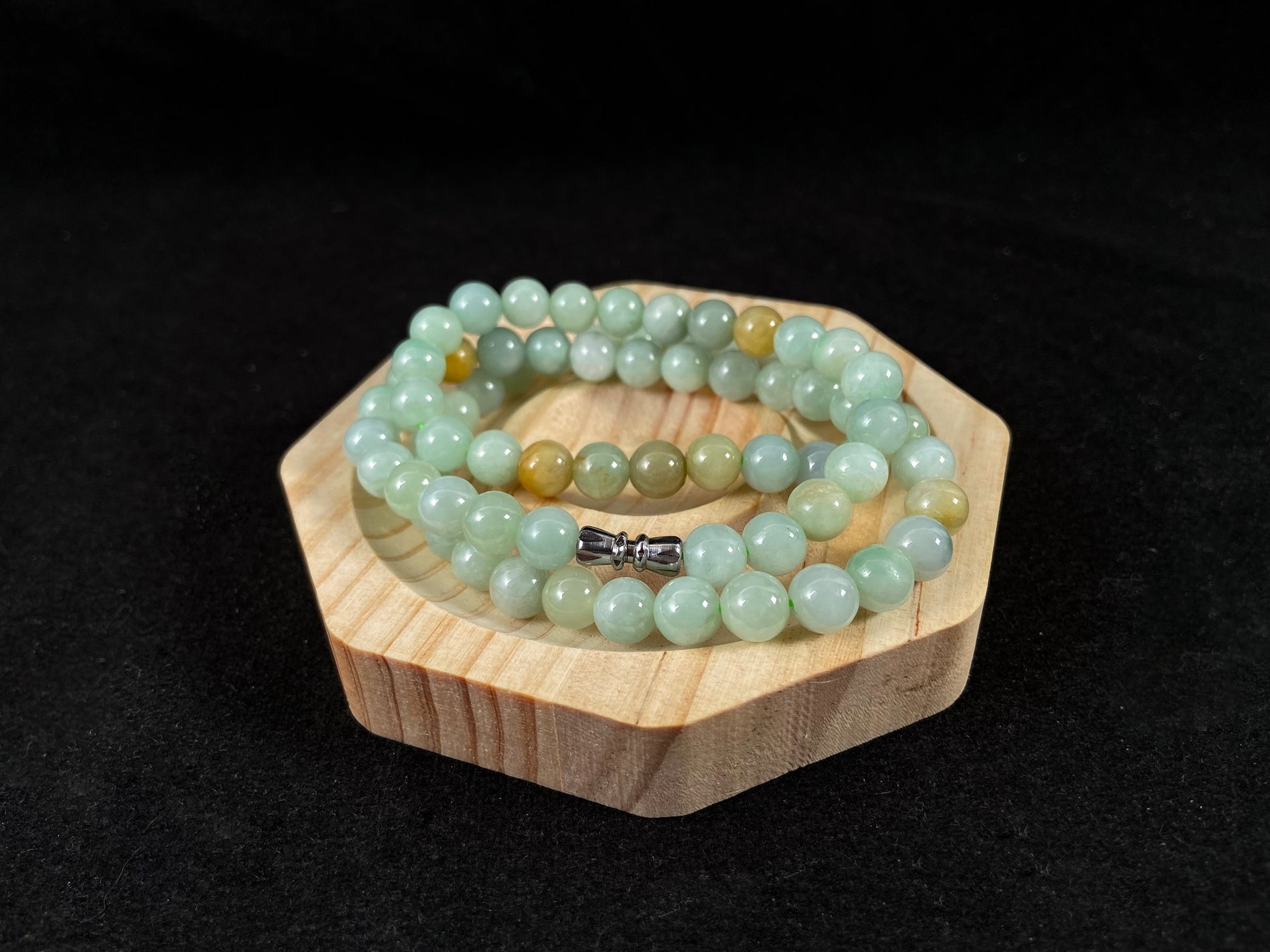 A light green jade bead strand with subtle tan brown accents.