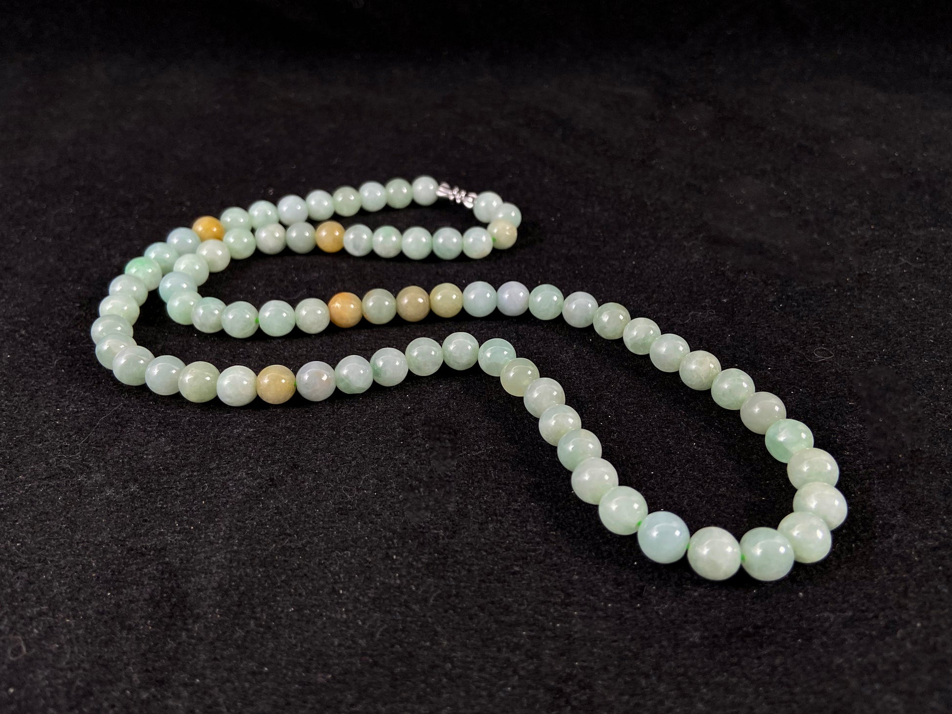 A light green jade bead strand with subtle tan brown accents.