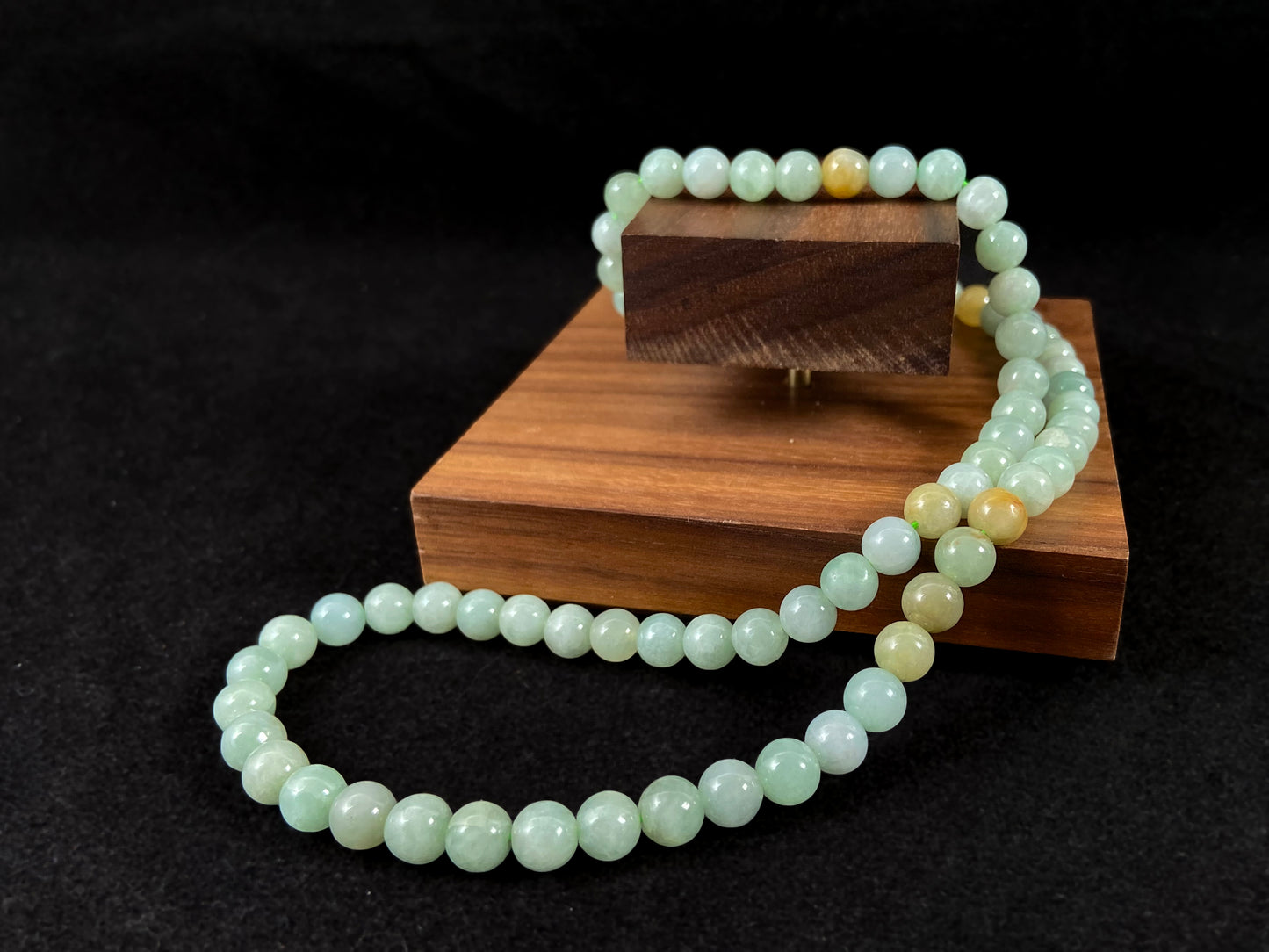 A light green jade bead strand with subtle tan brown accents.