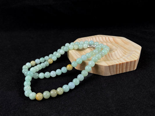 A light green jade bead strand with subtle tan brown accents.