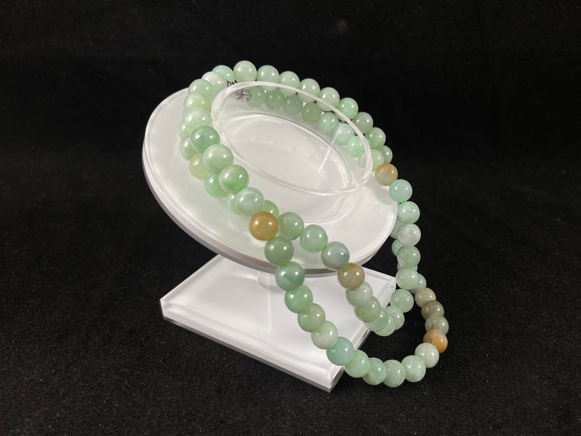 A light green jade bead strand with subtle tan brown accents.