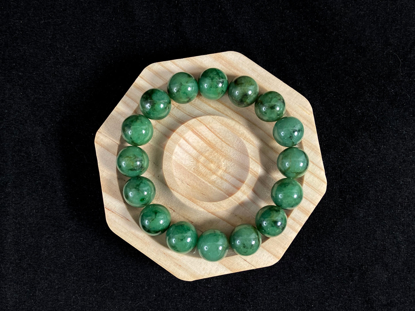 A strand of uniform jade beads in pale green with brownish green and deep green accents.