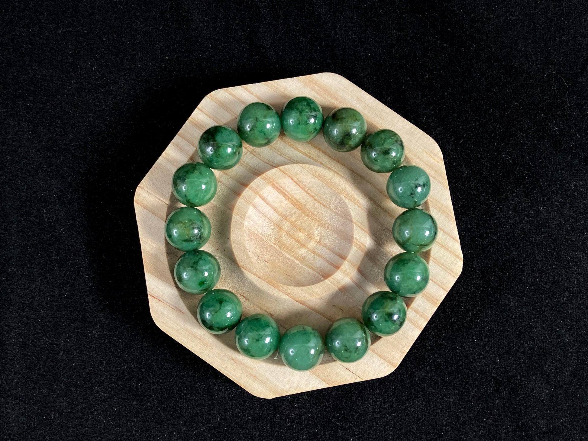 A strand of uniform jade beads in pale green with brownish green and deep green accents.
