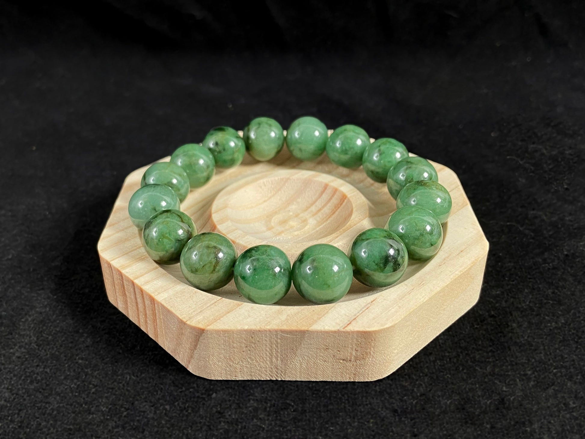 A strand of uniform jade beads in pale green with brownish green and deep green accents.