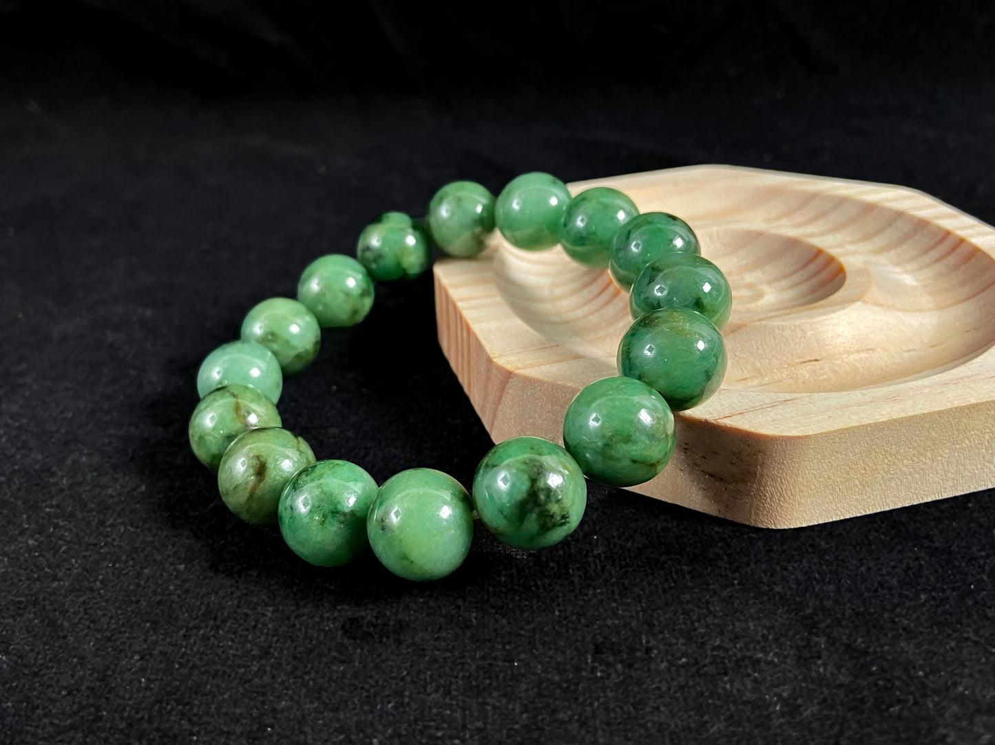 A strand of uniform jade beads in pale green with brownish green and deep green accents.