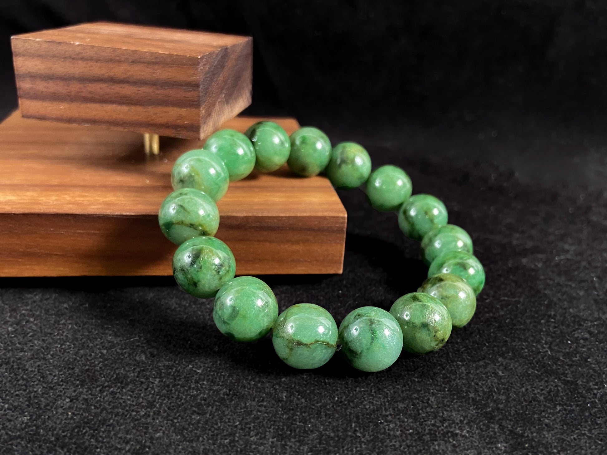 A strand of uniform jade beads in pale green with brownish green and deep green accents.