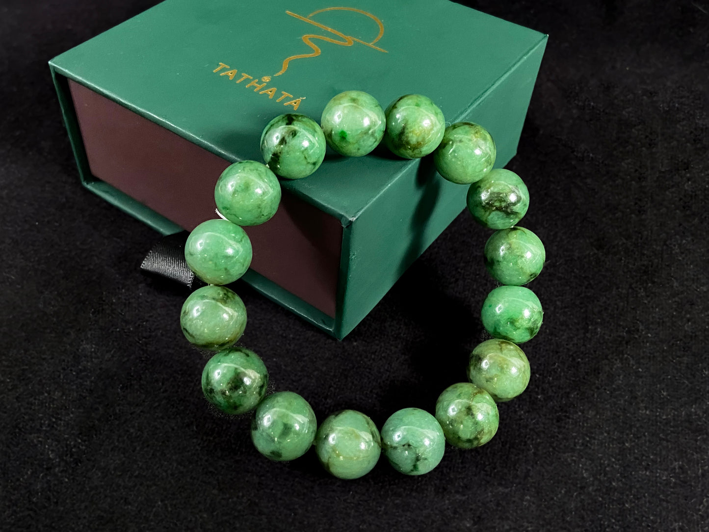 A strand of uniform jade beads in pale green with brownish green and deep green accents.
