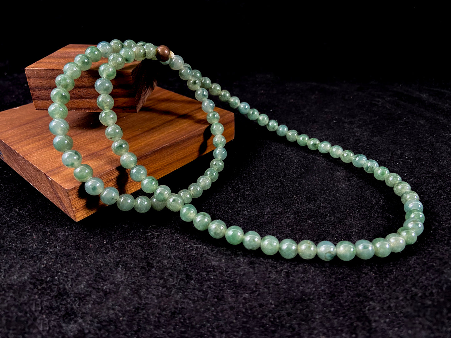 A strand of jade beads featuring a translucent light green base with deep green accents.