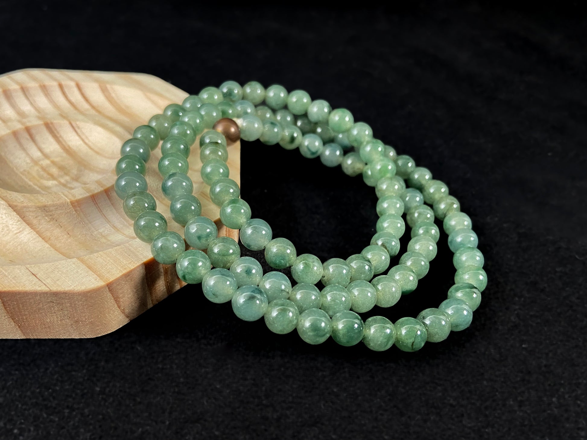 A strand of jade beads featuring a translucent light green base with deep green accents.