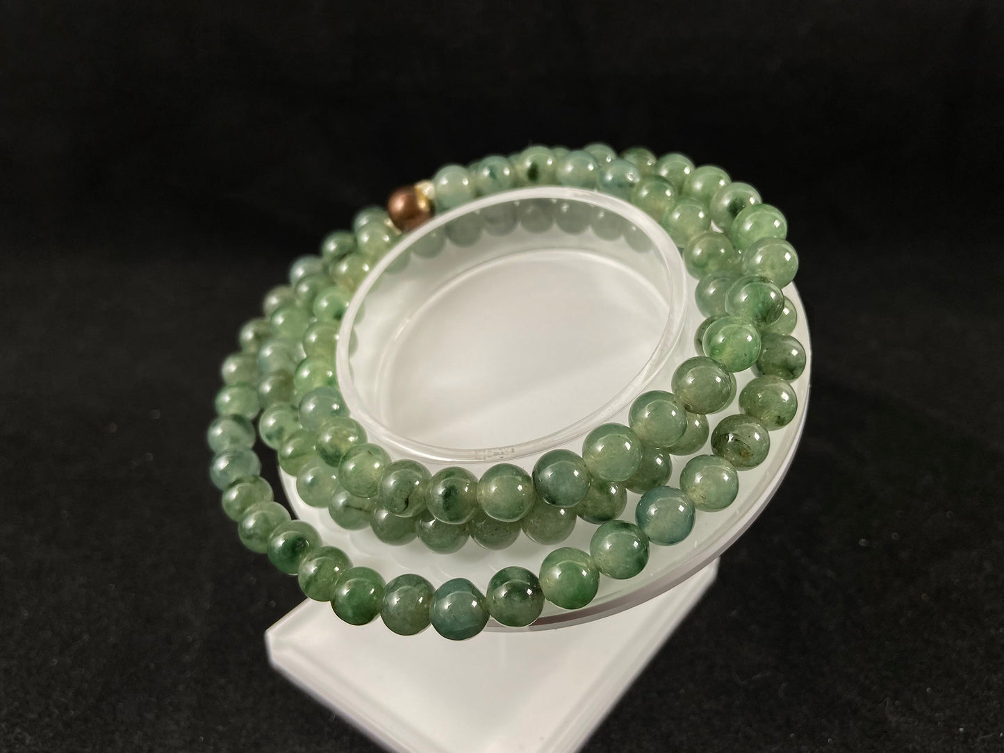 A strand of jade beads featuring a translucent light green base with deep green accents.