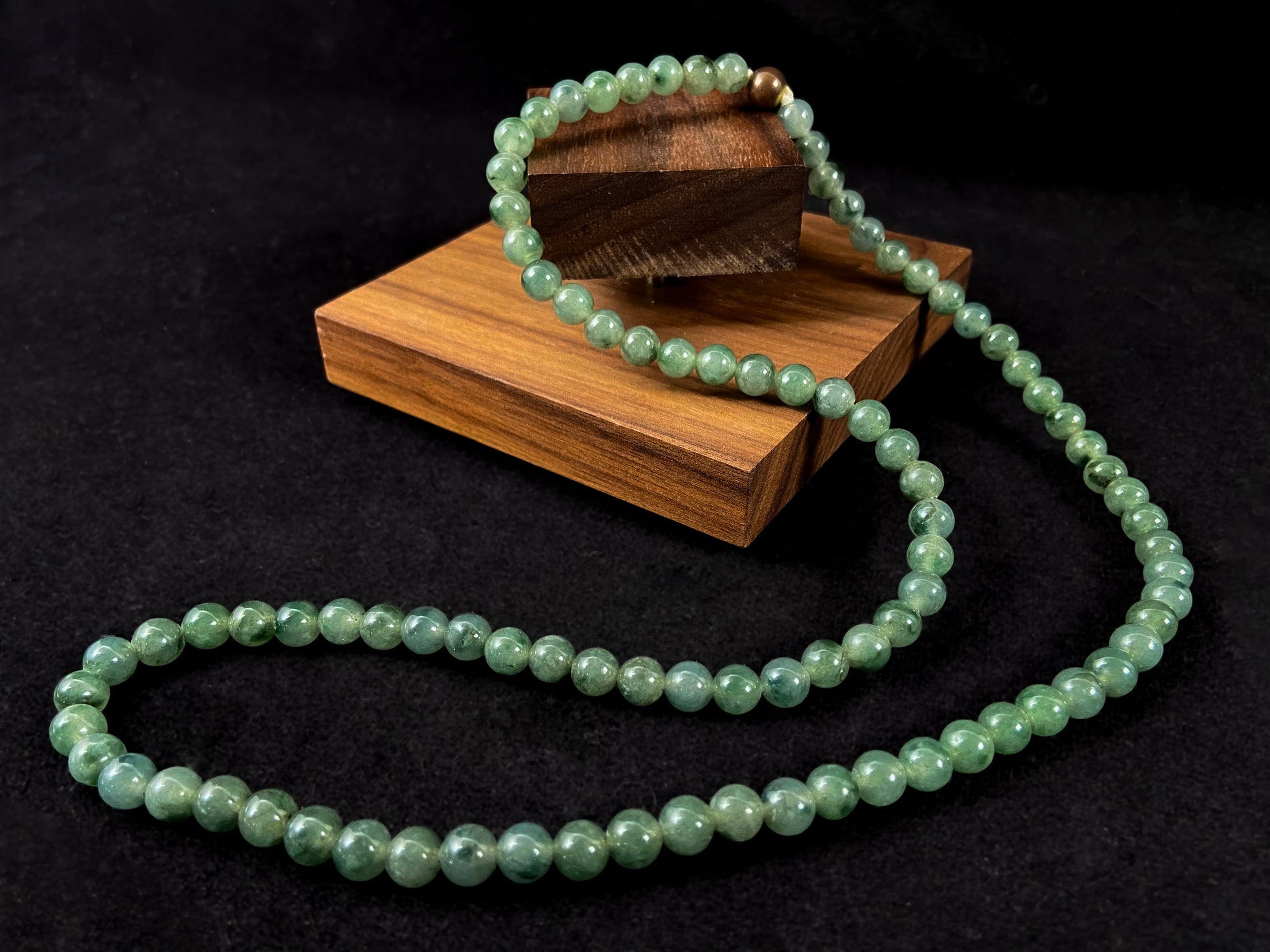 A strand of jade beads featuring a translucent light green base with deep green accents.