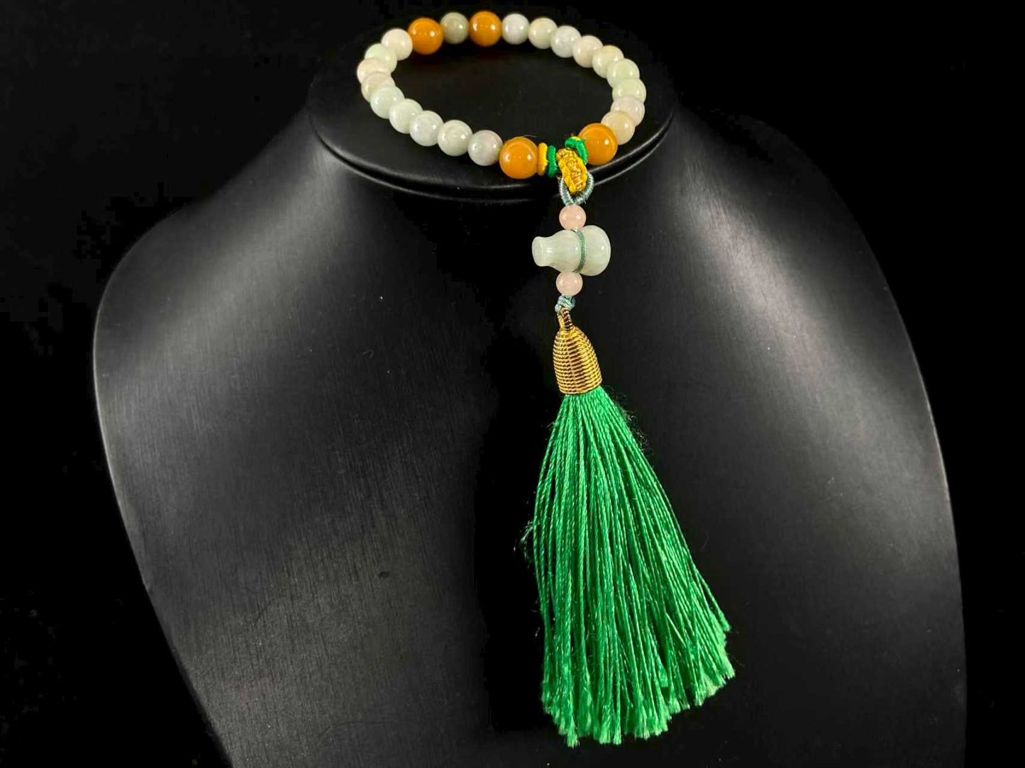 A milky white jade strand with gold, brown, and pink beads, gourd pendant, and green tassel.