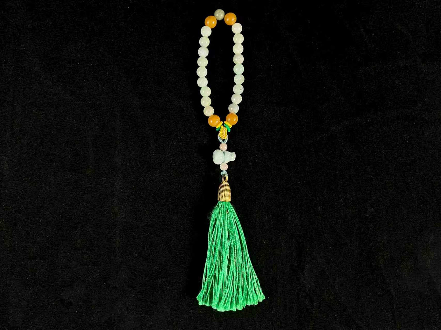 A milky white jade strand with gold, brown, and pink beads, gourd pendant, and green tassel.