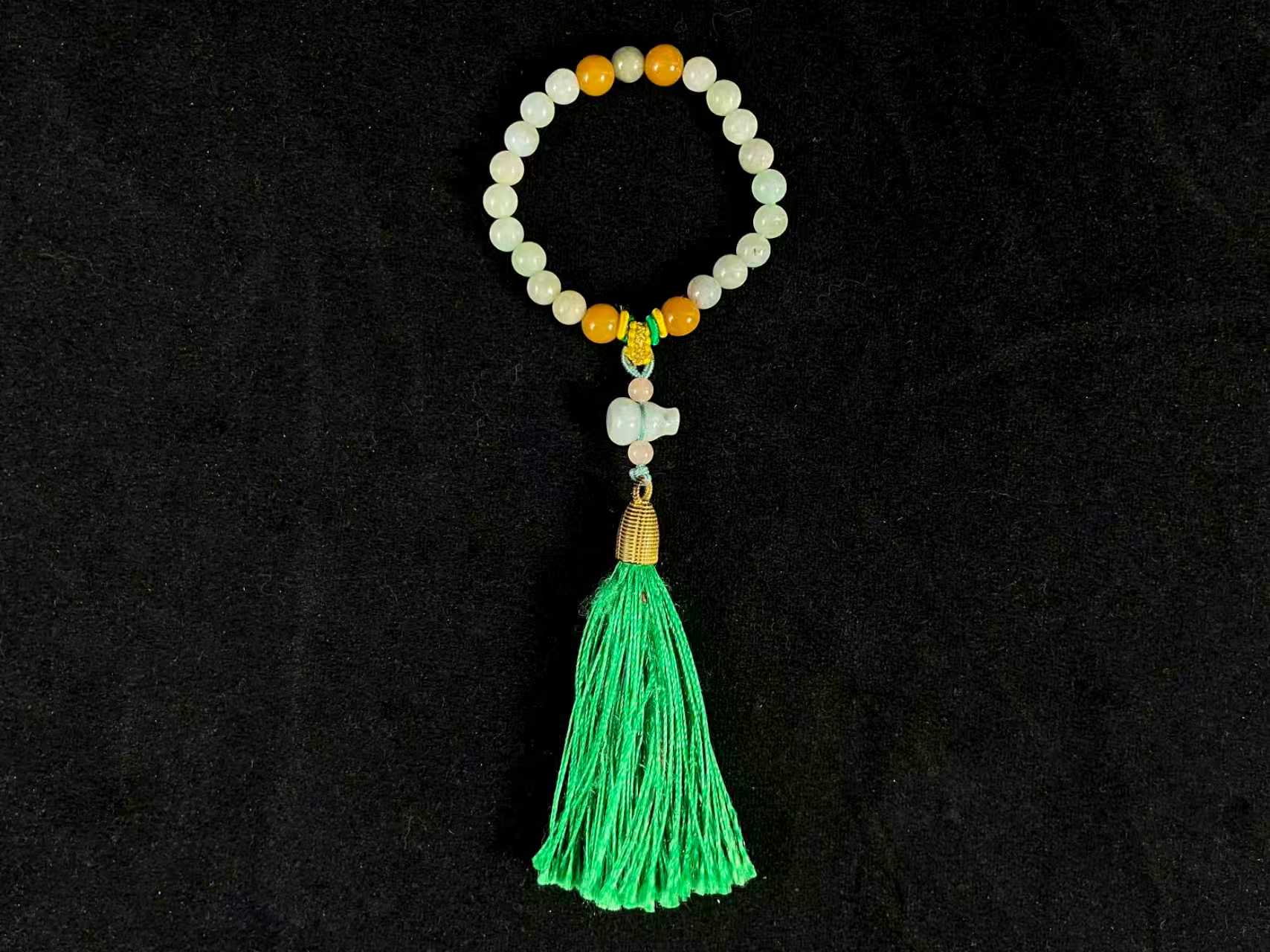 A milky white jade strand with gold, brown, and pink beads, gourd pendant, and green tassel.