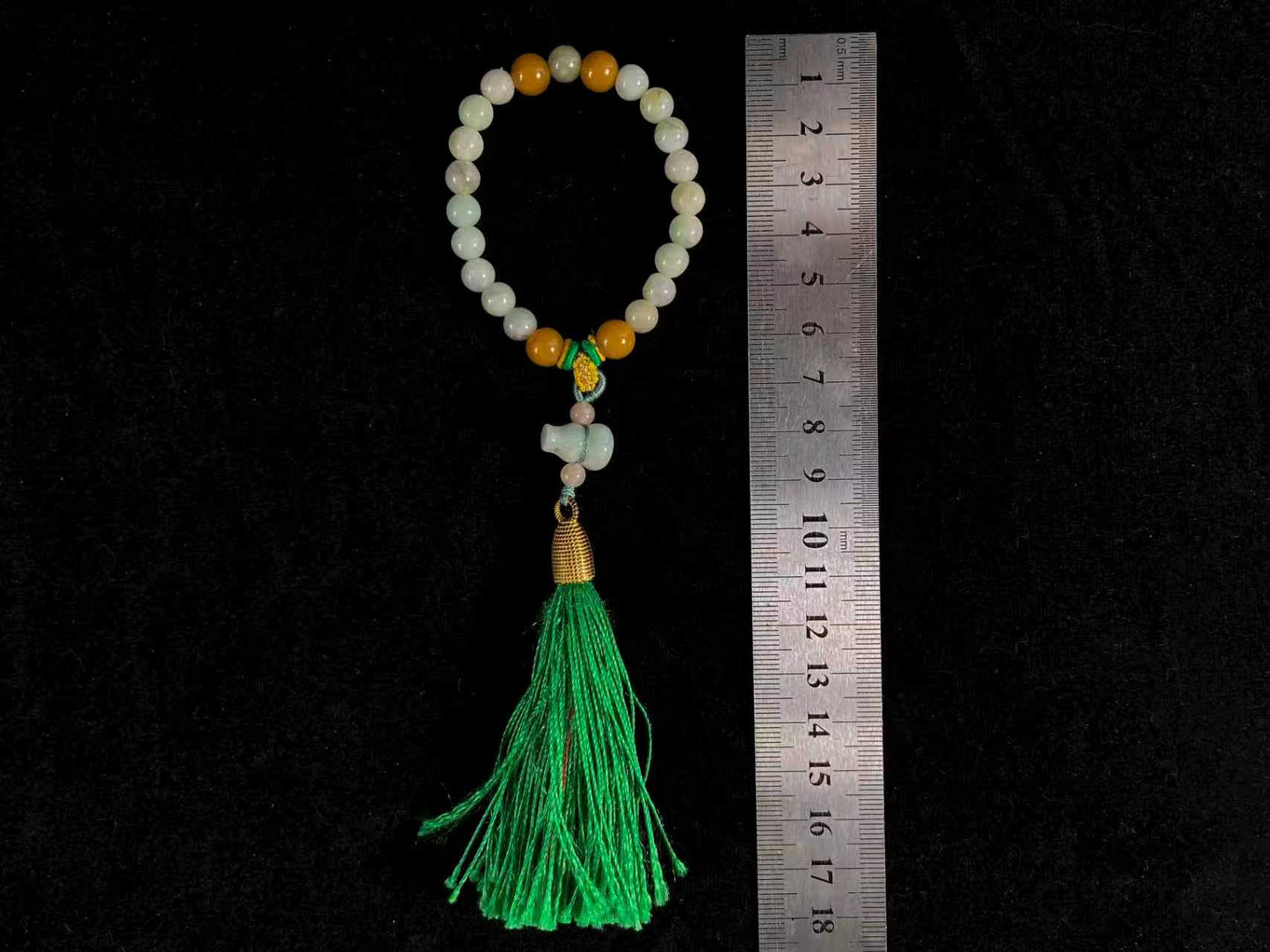 A milky white jade strand with gold, brown, and pink beads, gourd pendant, and green tassel.