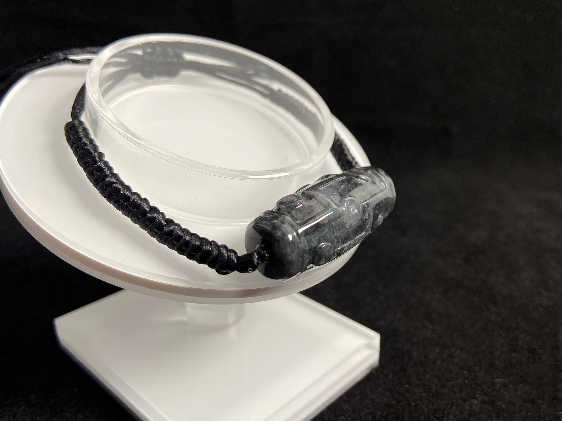 This braided bracelet combines a black cord with smooth gray "Lulutong" jade beads, creating a timeless and meaningful accessory.