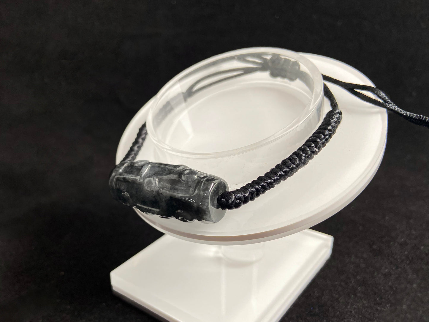 This braided bracelet combines a black cord with smooth gray "Lulutong" jade beads, creating a timeless and meaningful accessory.