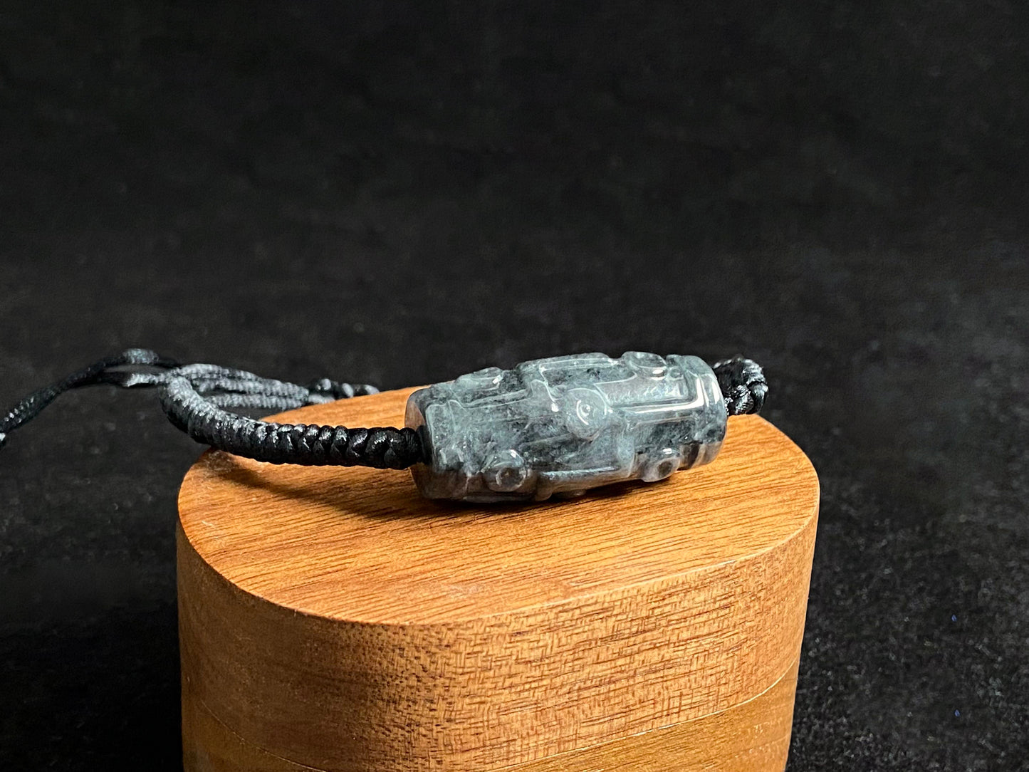 This braided bracelet combines a black cord with smooth gray "Lulutong" jade beads, creating a timeless and meaningful accessory.