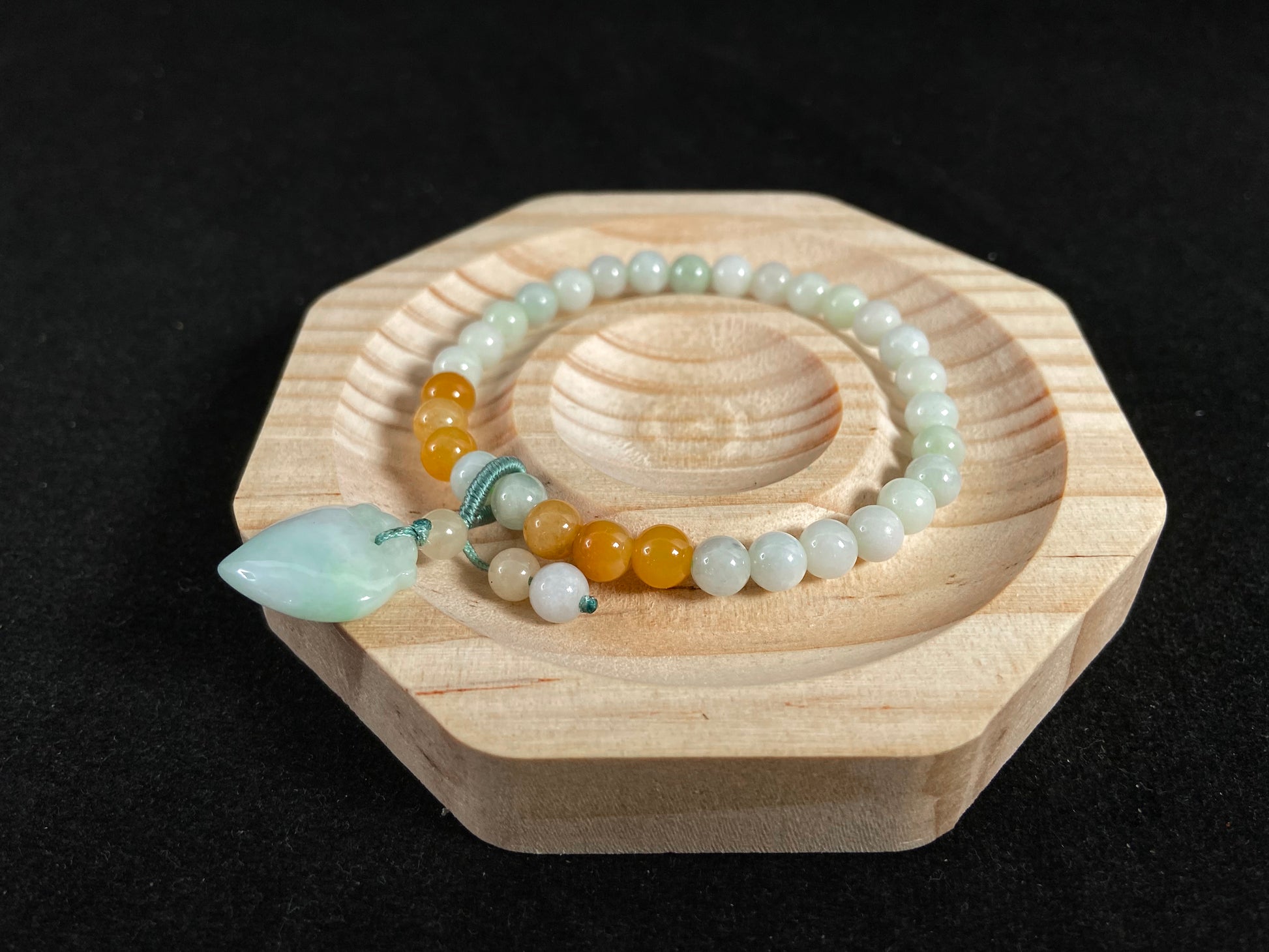 A jade bead strand with a white green peach pendant and tan/white green beads.