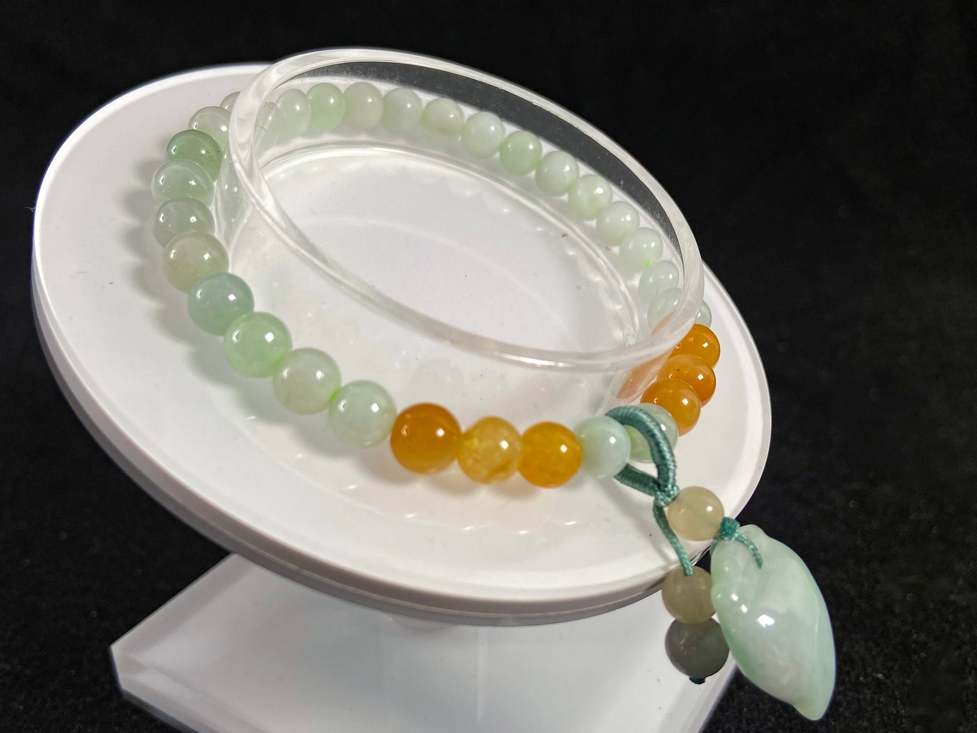 A jade bead strand with a white green peach pendant and tan/white green beads.