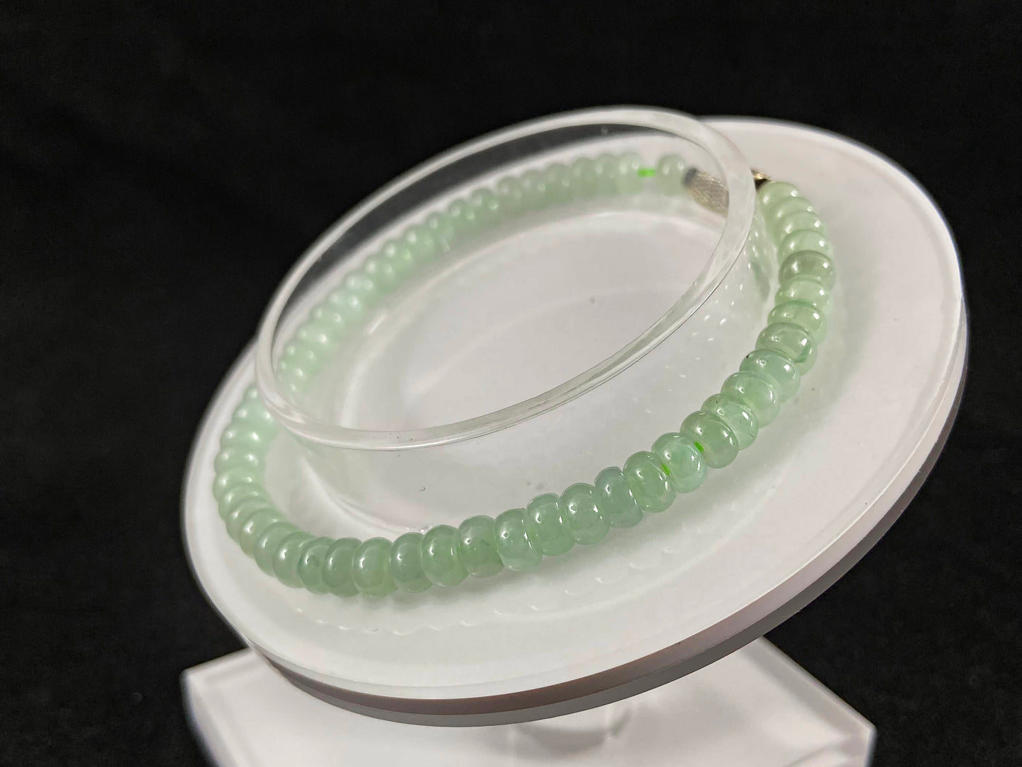 A strand of translucent light green oval jade beads.