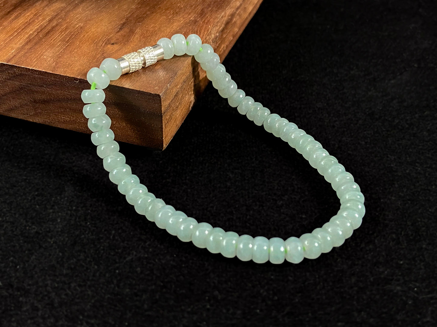 A strand of translucent light green oval jade beads.