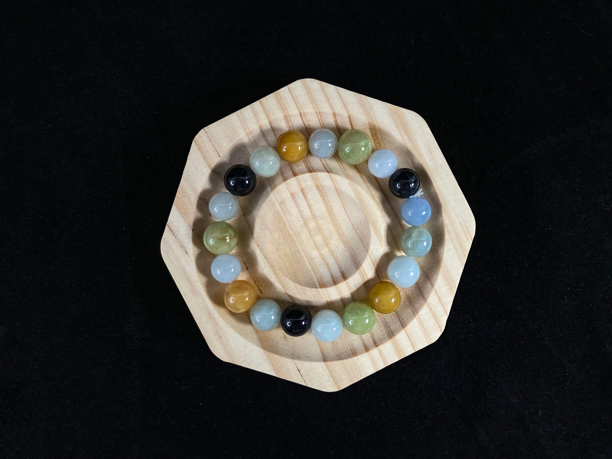 A jade bead strand in earthy brown, pure white, classic black, and ethereal blue-white.