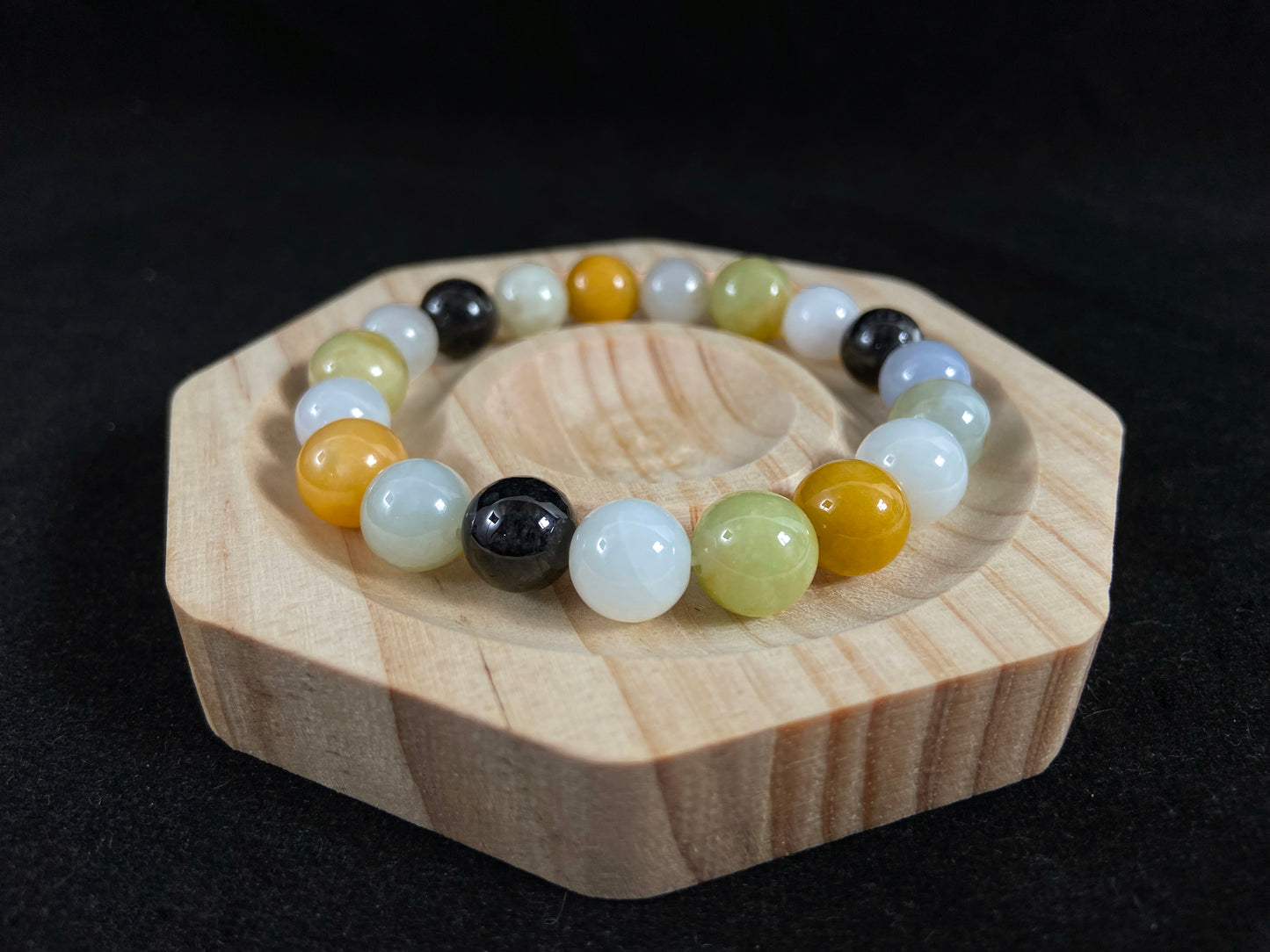 A jade bead strand in earthy brown, pure white, classic black, and ethereal blue-white.