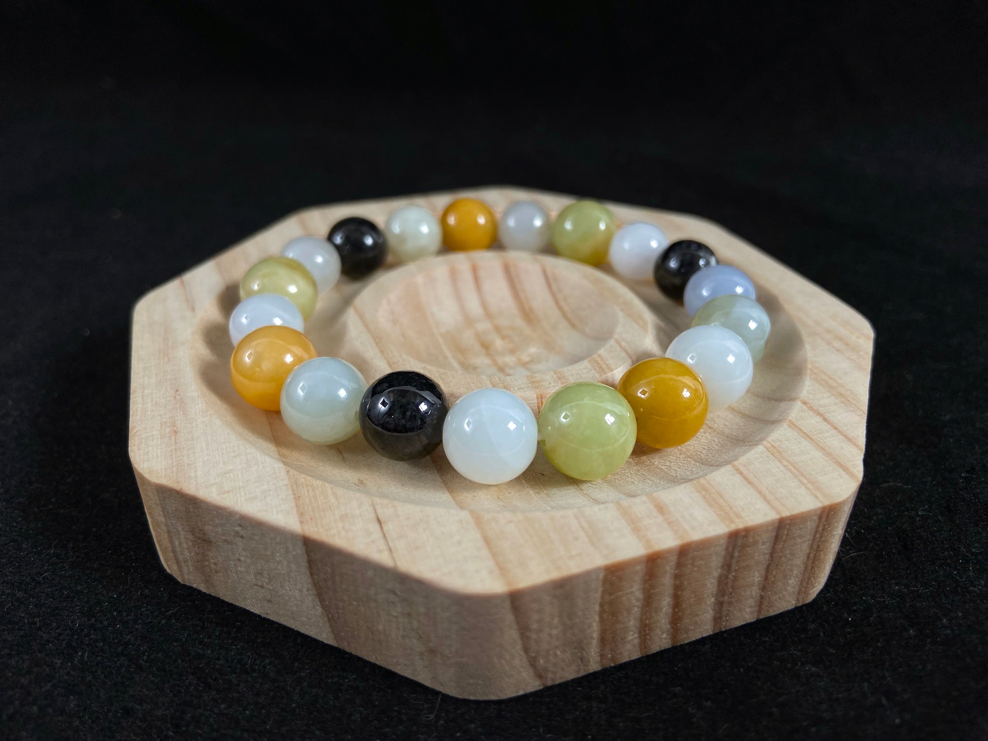 A jade bead strand in earthy brown, pure white, classic black, and ethereal blue-white.