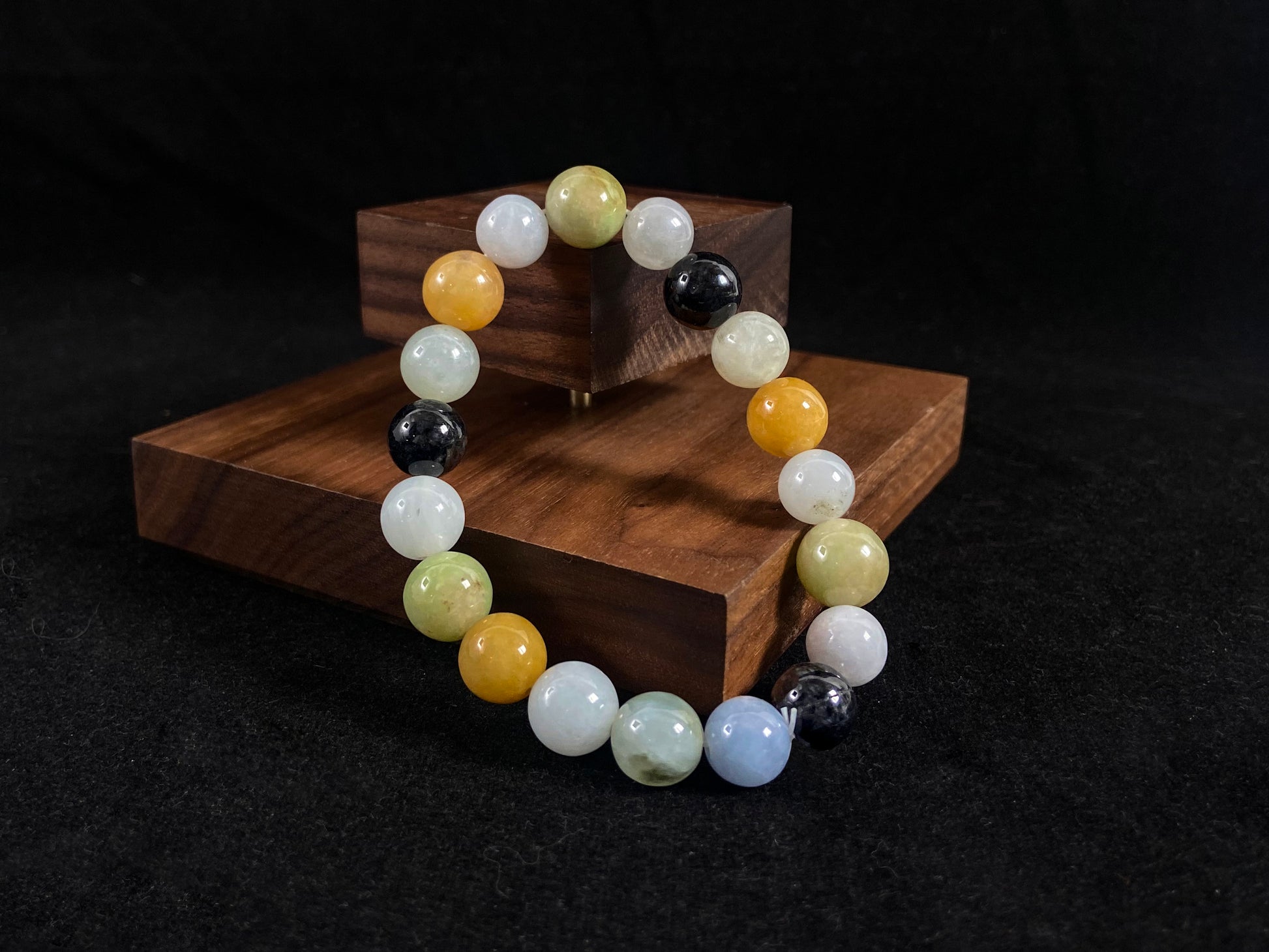 A jade bead strand in earthy brown, pure white, classic black, and ethereal blue-white.