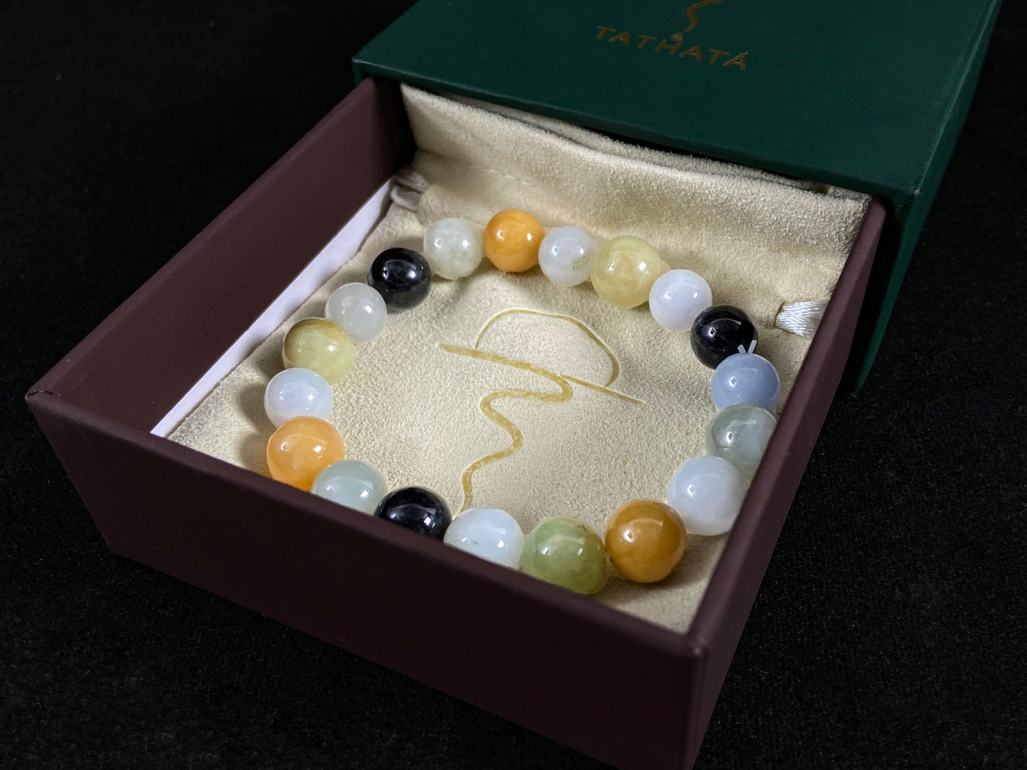 A jade bead strand in earthy brown, pure white, classic black, and ethereal blue-white.