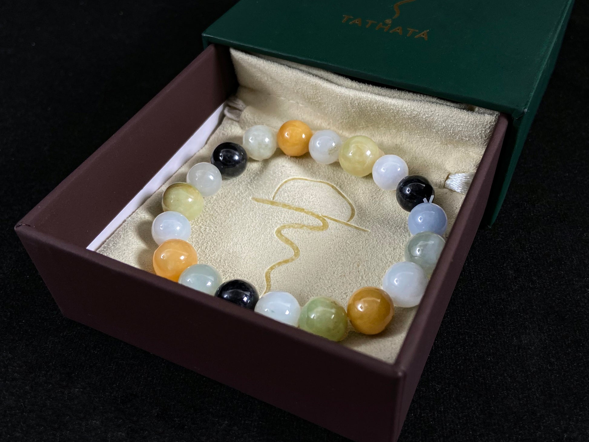 A jade bead strand in earthy brown, pure white, classic black, and ethereal blue-white.