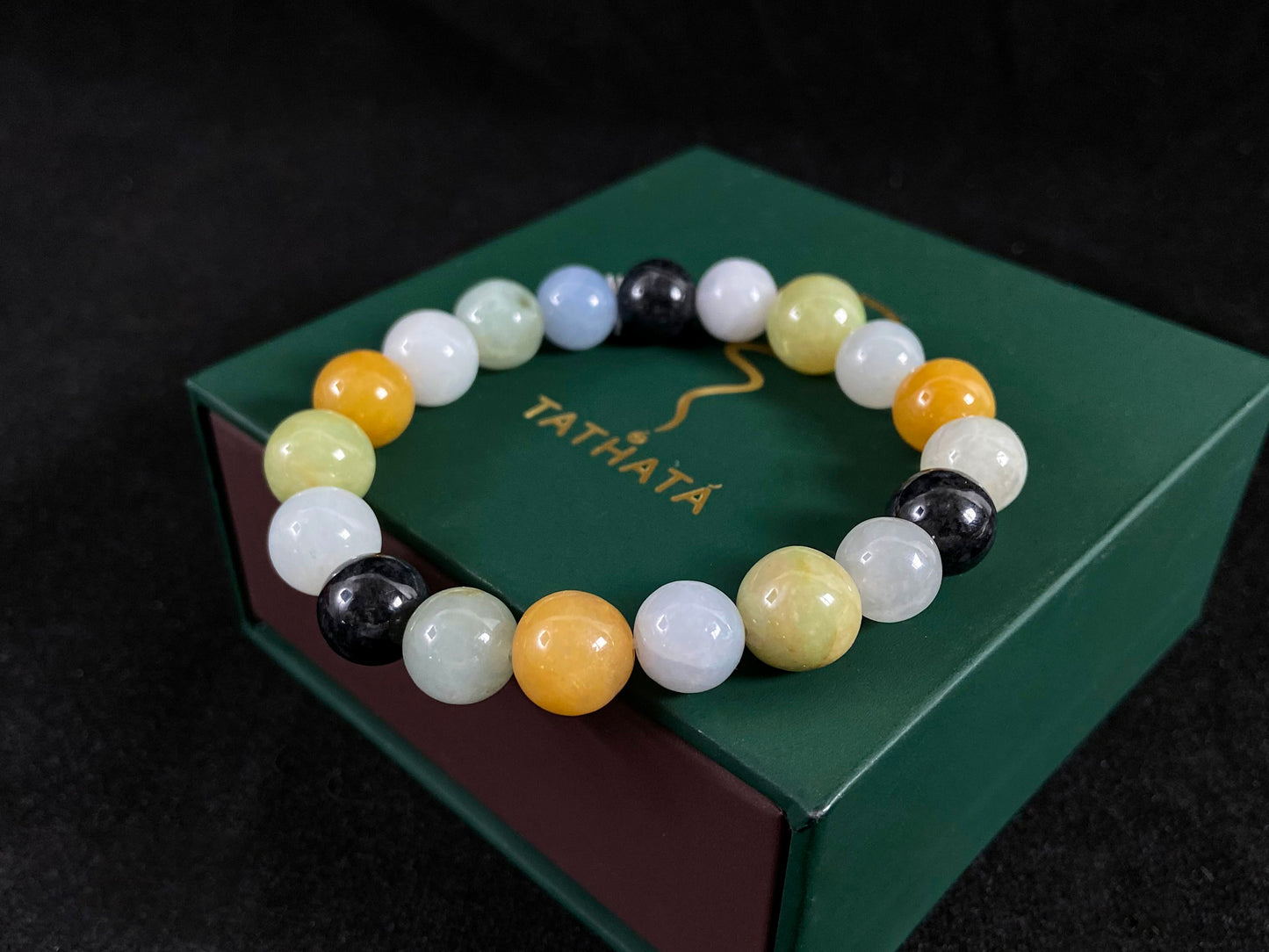 A jade bead strand in earthy brown, pure white, classic black, and ethereal blue-white.