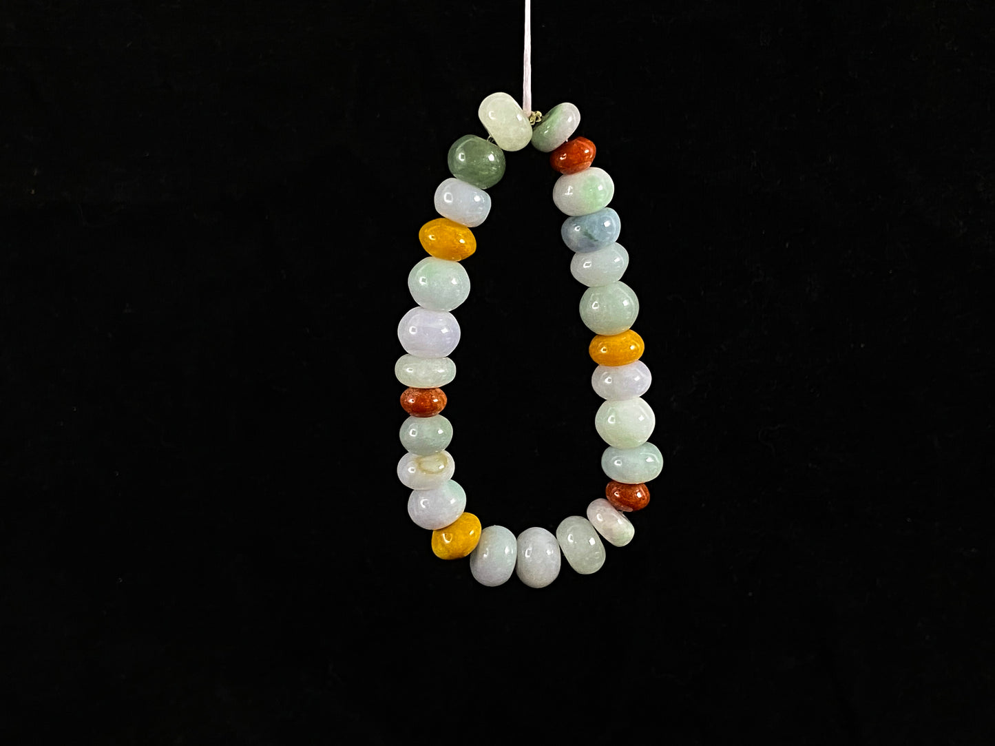 A strand of irregular abacus-shaped jade beads in creamy white, forest green, reddish brown, yellow, tan and light green.
