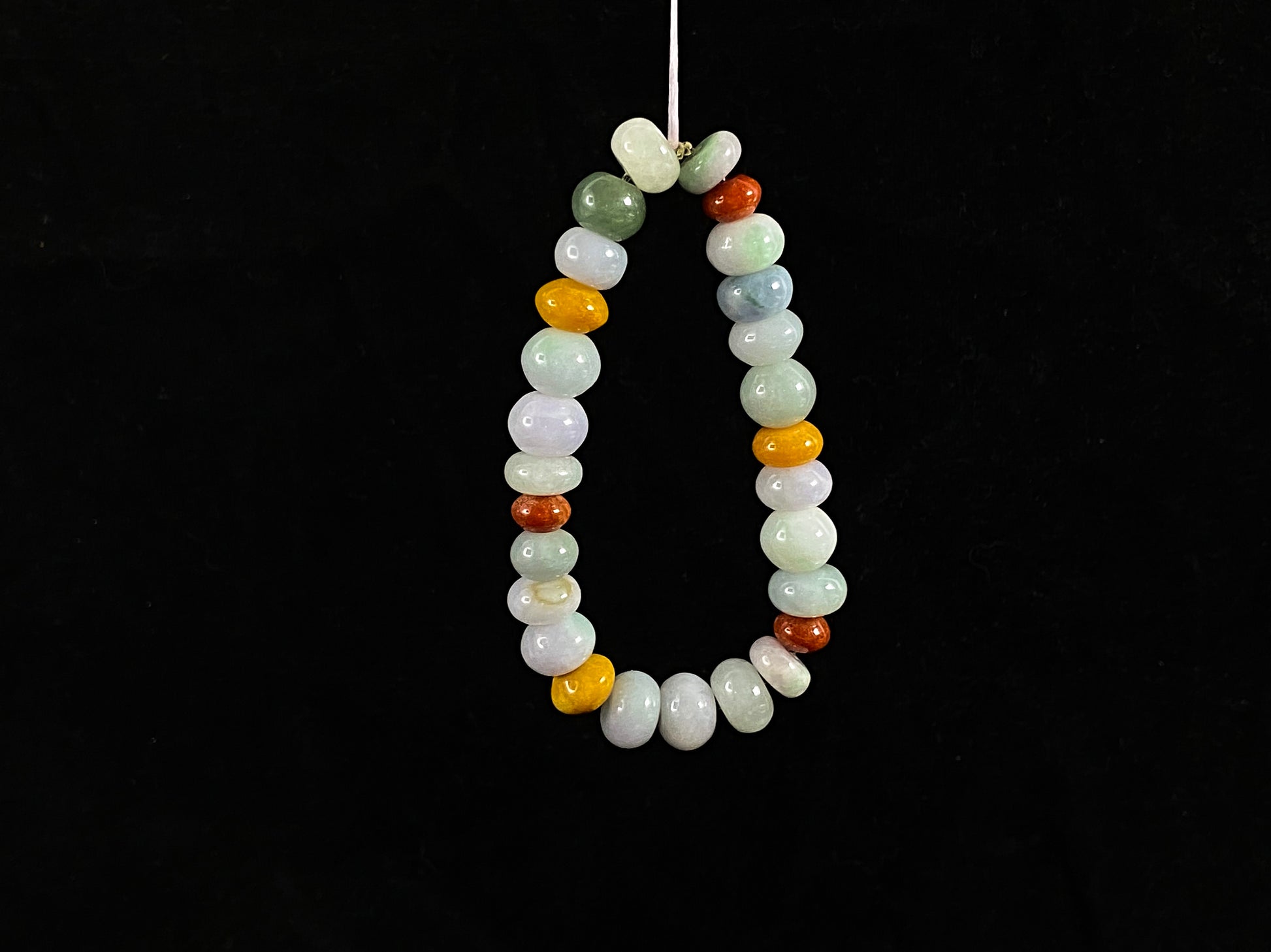 A strand of irregular abacus-shaped jade beads in creamy white, forest green, reddish brown, yellow, tan and light green.