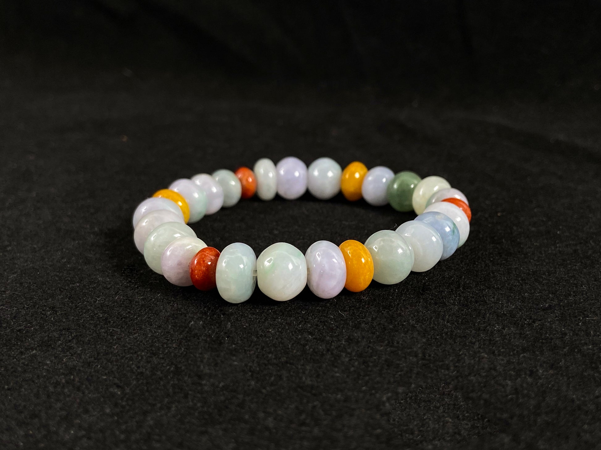 A strand of irregular abacus-shaped jade beads in creamy white, forest green, reddish brown, yellow, tan and light green.